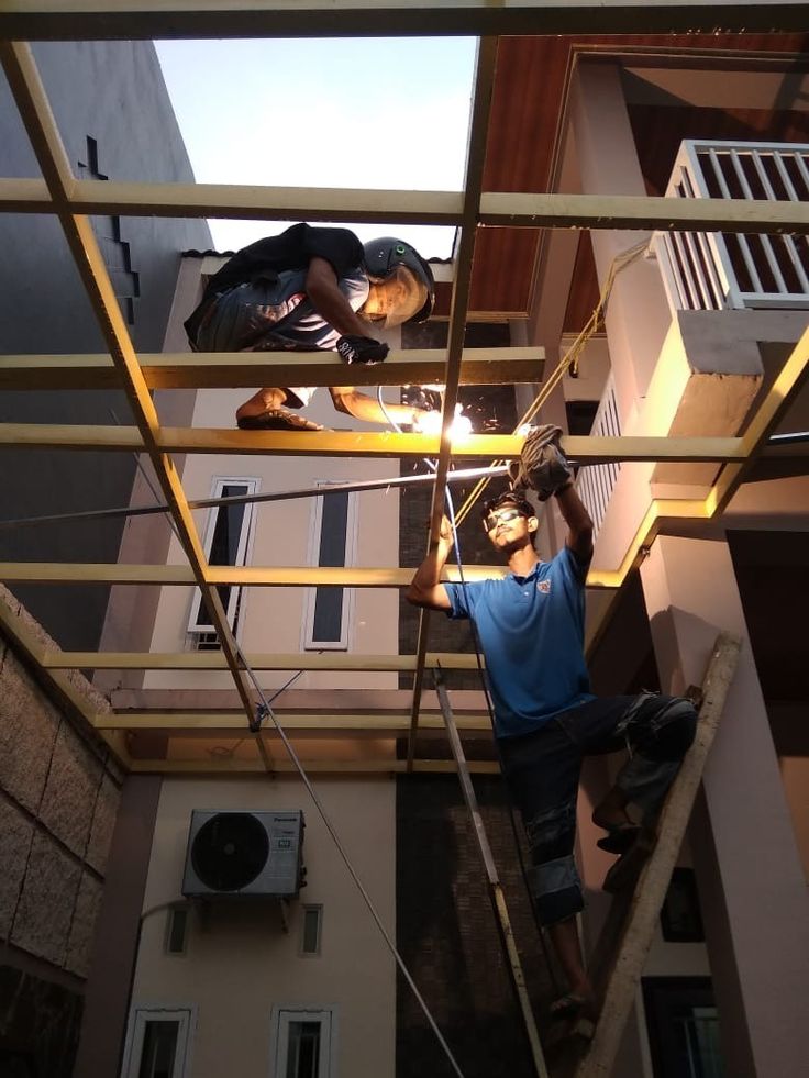 Jasa pasang kanopi oleh bengkel kanopi termurah – dua teknisi sedang melakukan pemasangan rangka kanopi rumah dalam promo pasang kanopi spesial.
