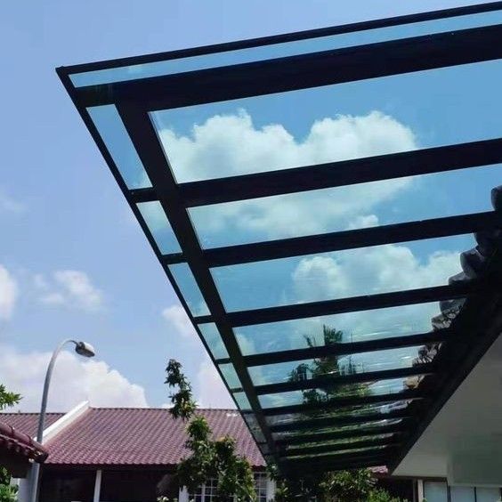 Kanopi Polycarbonate transparan tahan panas dan bising, dipasang di halaman depan rumah bergaya tropis.