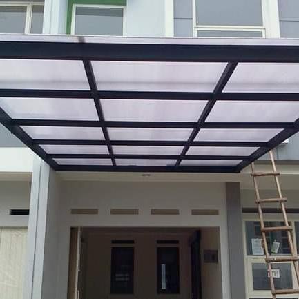 Kanopi transparan Twinlite dengan rangka besi hitam di depan rumah minimalis, memberikan pencahayaan alami dan tampilan modern pada area balkon.