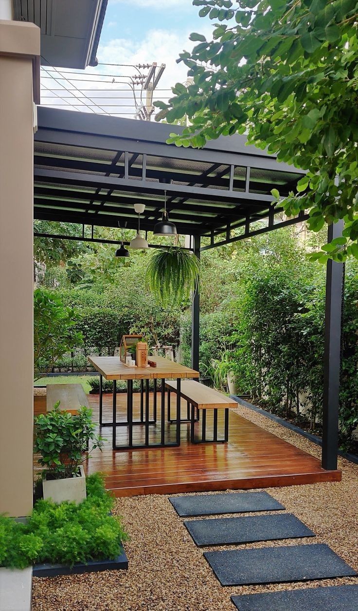Kanopi modern di area taman belakang dengan rangka besi hitam dan atap transparan, menciptakan ruang santai outdoor yang menambah nilai properti.