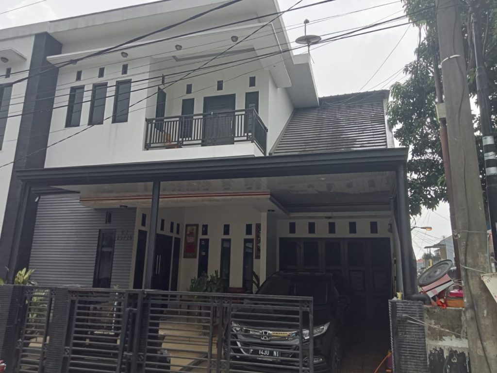 Tampilan depan rumah dua lantai setelah pemasangan kanopi carport berwarna hitam, memberikan perlindungan penuh untuk area parkir dan menambah kesan modern.