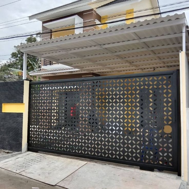 Kanopi anti bising dengan atap spandek gelombang pada rumah minimalis modern, dilengkapi pagar motif laser cutting hitam elegan