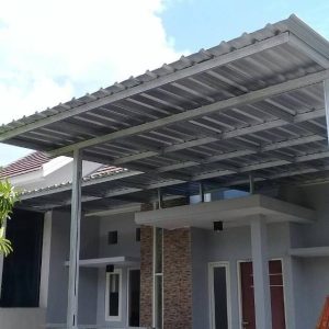 Kanopi baja ringan dengan atap alderon berwarna putih dipasang di area carport rumah minimalis dua lantai, memberikan perlindungan dari hujan dan panas dengan desain modern dan kokoh.