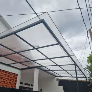 Kanopi polycarbonate rangka besi hollow hitam – cocok untuk carport rumah modern, tahan cuaca dan tetap terang berkat material transparan.