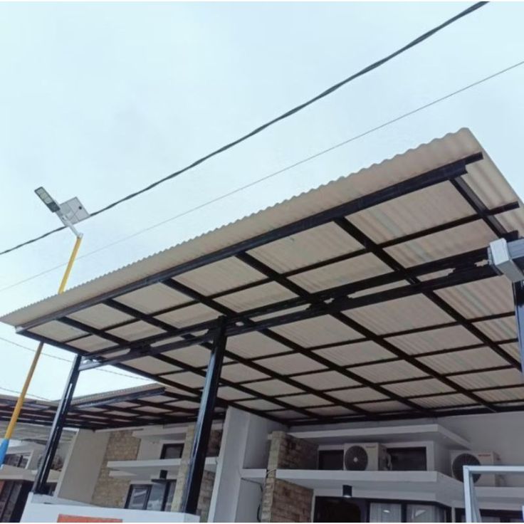 Kanopi tidak berisik saat hujan dengan atap UPVC bergelombang warna krem dan rangka besi hitam minimalis di rumah modern.