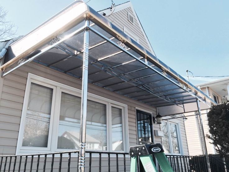 Kanopi rumah dengan struktur stainless steel mengilap dan atap transparan, tampil elegan dan tahan karat di segala cuaca.