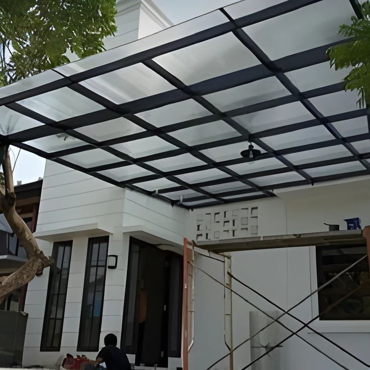 Kanopi Kaca Akrilik Pekerja memperbaiki kanopi polycarbonate di rumah modern, solusi untuk mengatasi kanopi bocor saat hujan deras.