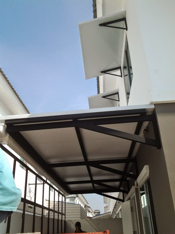 Kanopi Sling Desain kanopi minimalis modern dengan rangka besi dan atap solid putih, solusi stylish dan fleksibel untuk area sempit antar bangunan.